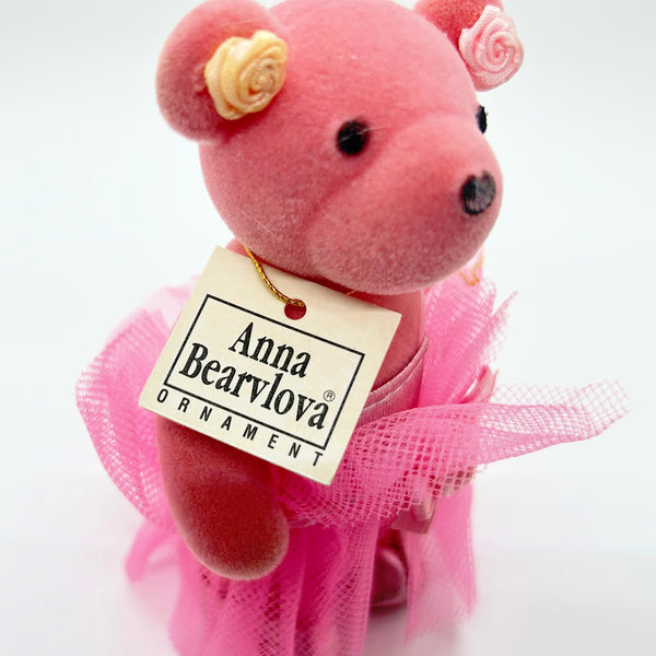 A pink plush teddy bear ornament wearing a pink tulle tutu and holding a paper tag that reads 'Anna Bearylova ORNAMENT', photographed on a plain white background.