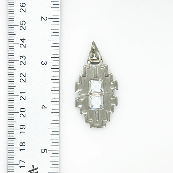 You'll draw attention and compliments with this striking art deco pendant. Its elongated diamond rectangle shape is adorned with dazzling crystals and two sparkling square stones at the center. 