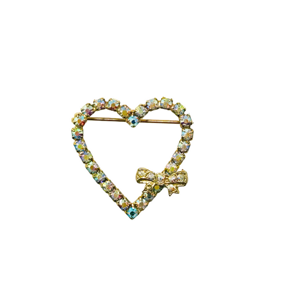 This charming mid-century brooch captures all the sparkle and romance of vintage glamour. The delicate gold-tone heart showcases shimmering aurora borealis rhinestones that dance with rainbow fire, while a sweet bow accent adds an extra touch of whimsy.