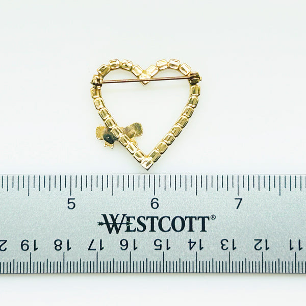 This charming mid-century brooch captures all the sparkle and romance of vintage glamour. The delicate gold-tone heart showcases shimmering aurora borealis rhinestones that dance with rainbow fire, while a sweet bow accent adds an extra touch of whimsy.