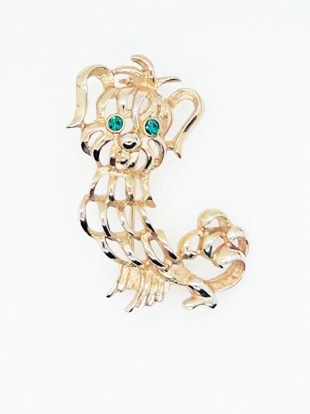 This endearing vintage dog brooch captures a pup with luxuriant ears and brilliant green rhinestone eyes, poised with anticipation. Measuring 1.75" tall, it is engraved with the name Avon in bold, capital letters. Captivating and classic vintage dog brooch with stunning green rhinestone eyes, and a must-have for any dog lover.