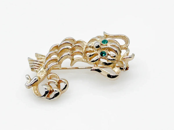 This endearing vintage dog brooch captures a pup with luxuriant ears and brilliant green rhinestone eyes, poised with anticipation. Measuring 1.75" tall, it is engraved with the name Avon in bold, capital letters. Captivating and classic vintage dog brooch with stunning green rhinestone eyes, and a must-have for any dog lover.