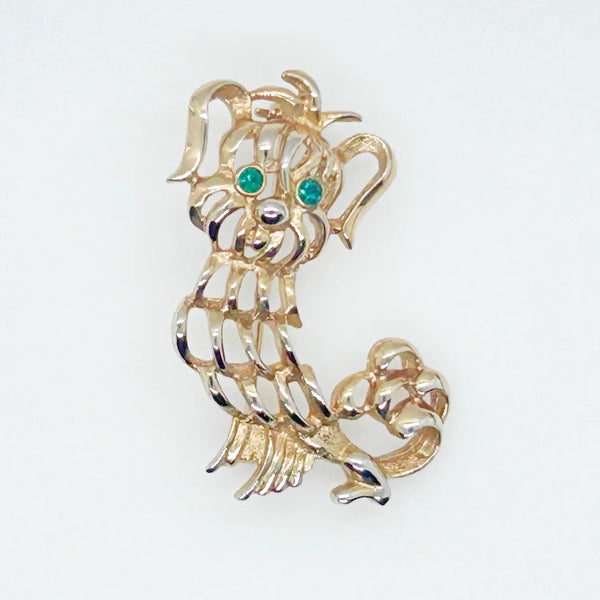 This endearing vintage dog brooch captures a pup with luxuriant ears and brilliant green rhinestone eyes, poised with anticipation. Measuring 1.75" tall, it is engraved with the name Avon in bold, capital letters. Captivating and classic vintage dog brooch with stunning green rhinestone eyes, and a must-have for any dog lover.