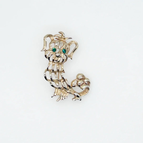 This endearing vintage dog brooch captures a pup with luxuriant ears and brilliant green rhinestone eyes, poised with anticipation. Measuring 1.75" tall, it is engraved with the name Avon in bold, capital letters. Captivating and classic vintage dog brooch with stunning green rhinestone eyes, and a must-have for any dog lover.