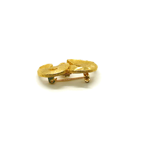 A small, vintage gold-tone initial "E" cursive monogram brooch pin, featuring a dual-textured finish with brushed matte styling and diamond-cut highlights on a plain white background