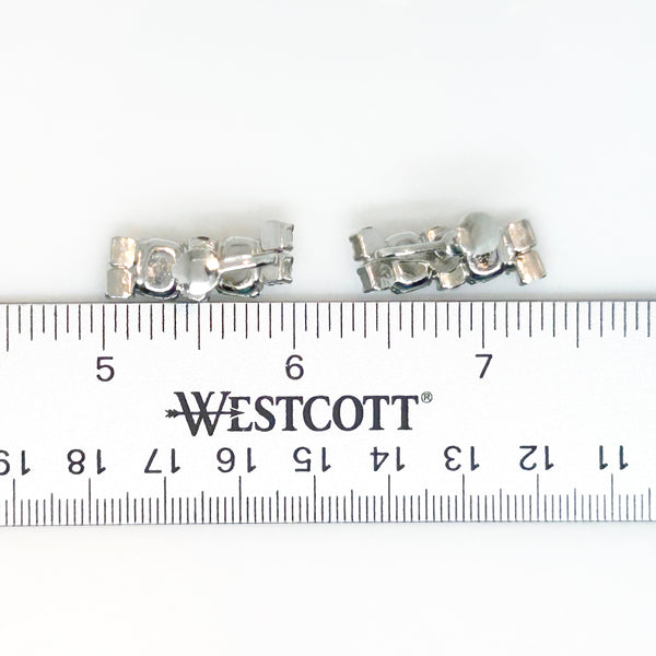  The earrings feature a unique stacked, half-hoop design. Emerald-cut stones elegantly alternate with two small, round stones, creating a captivating contrast. 