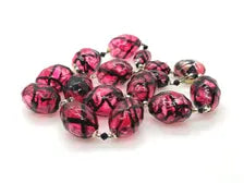 A cluster of round glass beads with a glossy pink and black marbled pattern, set against a plain white background.