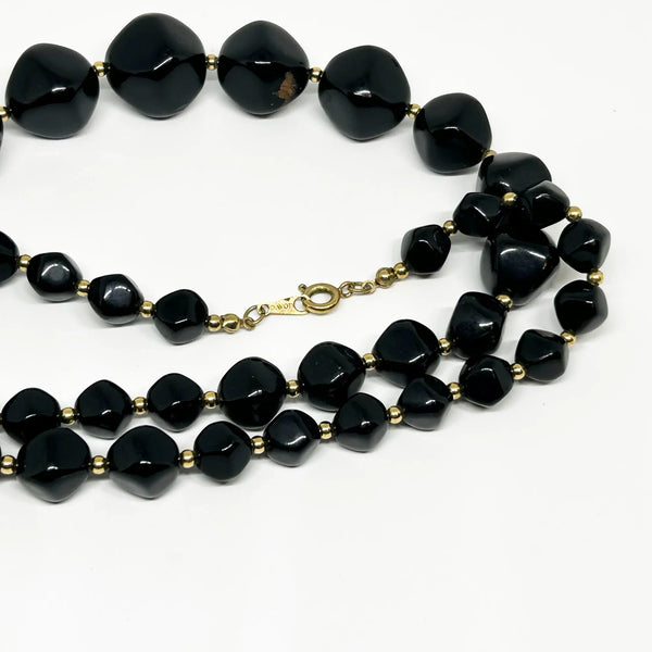 This unusual and striking vintage Avon necklace is made of graduated, asymmetrical black beads with gold-tone bead separators. It dates to the mid-1980's, is signed Avon in block letters on the spring clasp, and measures 24" long.