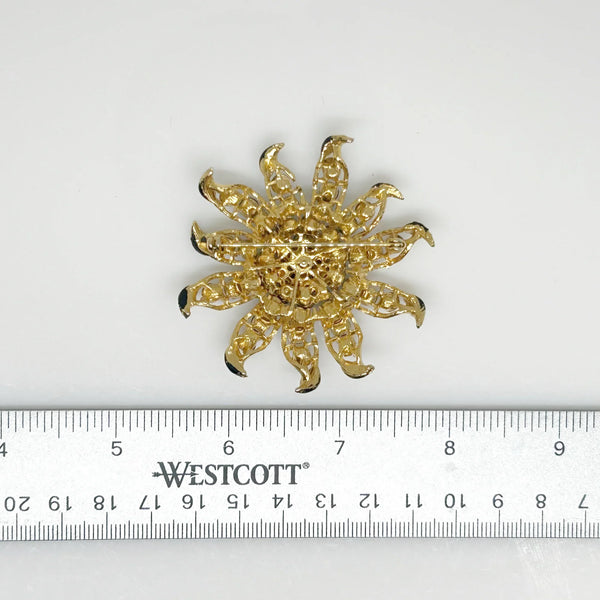 This exquisite vintage brooch captures the radiant beauty of the sun or a blooming flower with its intricate design. Crafted with precision, the gold rays or petals are elegantly studded with shimmering black faceted stones, adding depth and contrast. The tips are delicately finished with black enamel, enhancing its striking appearance.