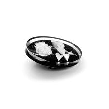 oval cameo brooch depicting a white rose with leaves carved against a dark, polished background. 