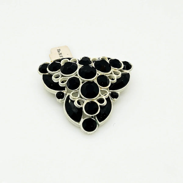This is a highly unusual vintage brooch made of a white enamel frame and set with black faceted stones. It still retains the store tag. 