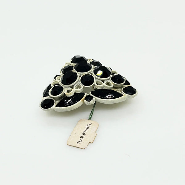 This is a highly unusual vintage brooch made of a white enamel frame and set with black faceted stones. It still retains the store tag. 