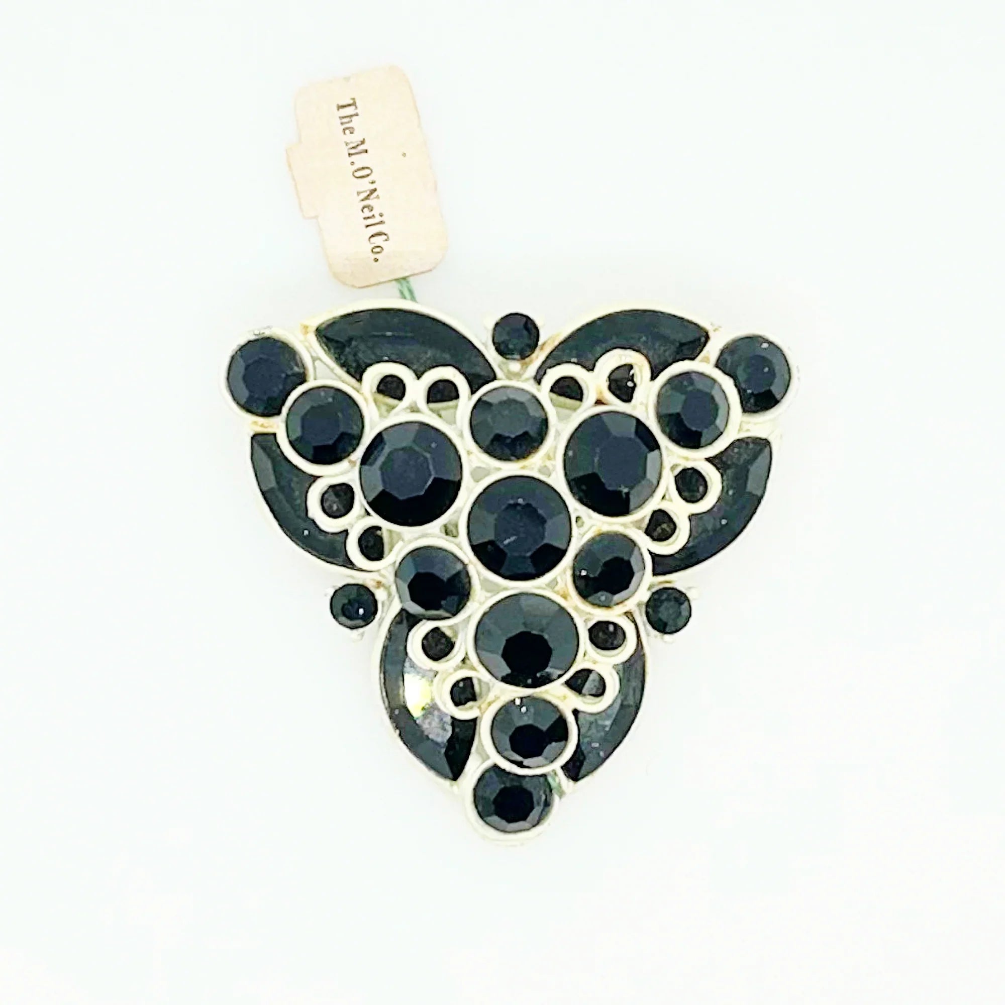 This is a highly unusual vintage brooch made of a white enamel frame and set with black faceted stones. It still retains the store tag. 