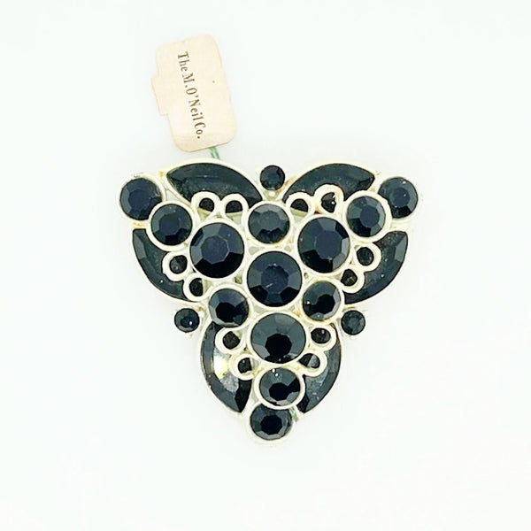 This is a highly unusual vintage brooch made of a white enamel frame and set with black faceted stones. It still retains the store tag. 