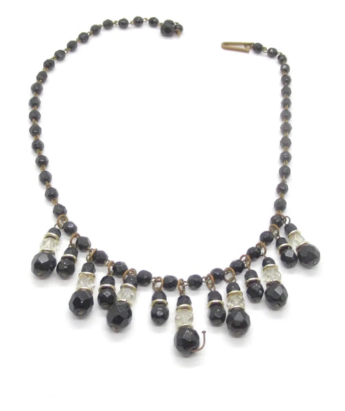 This wonderful vintage German bib necklace features black glass and clear beads in a choker or "Cleopatra fringe" style. These pieces are characterized by their intricate, cascading drop designs. 