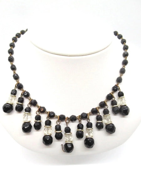 This wonderful vintage German bib necklace features black glass and clear beads in a choker or "Cleopatra fringe" style. These pieces are characterized by their intricate, cascading drop designs. 