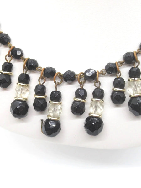 This wonderful vintage German bib necklace features black glass and clear beads in a choker or "Cleopatra fringe" style. These pieces are characterized by their intricate, cascading drop designs. 
