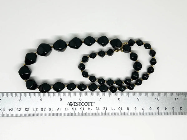 This unusual and striking vintage Avon necklace is made of graduated, asymmetrical black beads with gold-tone bead separators. It dates to the mid-1980's, is signed Avon in block letters on the spring clasp, and measures 24" long.