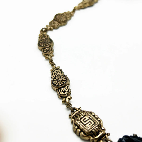 Vintage Art Deco choker necklace featuring gold-tone brass filigree links, two oval black beads, and a large textured black cluster central pendant