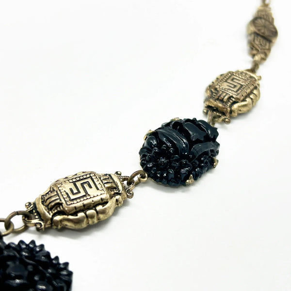 Vintage Art Deco choker necklace featuring gold-tone brass filigree links, two oval black beads, and a large textured black cluster central pendant