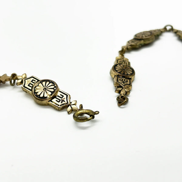 Vintage Art Deco choker necklace featuring gold-tone brass filigree links, two oval black beads, and a large textured black cluster central pendant