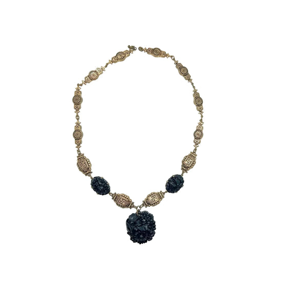An Art Deco  choker necklace with gold-tone filigree links and three dark, intricately carved floral beads, featuring a larger central pendant drop