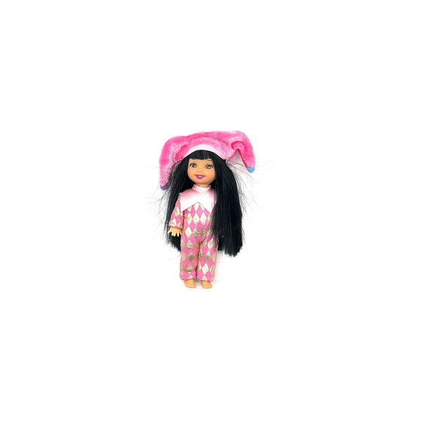 Front view of a vintage 1999 Mattel Barbie Kelly Club Jester Jenny miniature doll with long dark hair, dressed in a pink checkered jester costume and matching novelty hat, isolated on white
