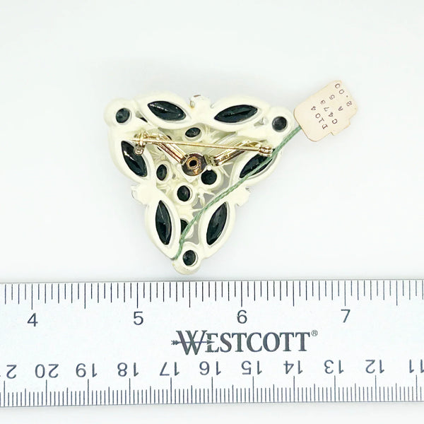 This is a highly unusual vintage brooch made of a white enamel frame and set with black faceted stones. It still retains the store tag. 