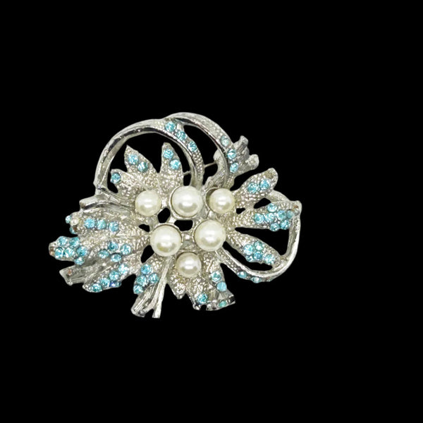With a touch of elegance, this vintage brooch boasts delicate power blue rhinestones accented by six lustrous faux pearls of different sizes.