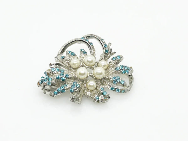 With a touch of elegance, this vintage brooch boasts delicate power blue rhinestones accented by six lustrous faux pearls of different sizes.