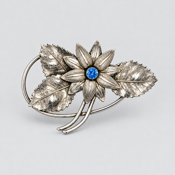 Vintage Silver-Tone Floral Brooch with Blue Rhinestone Center and Textured Leaves