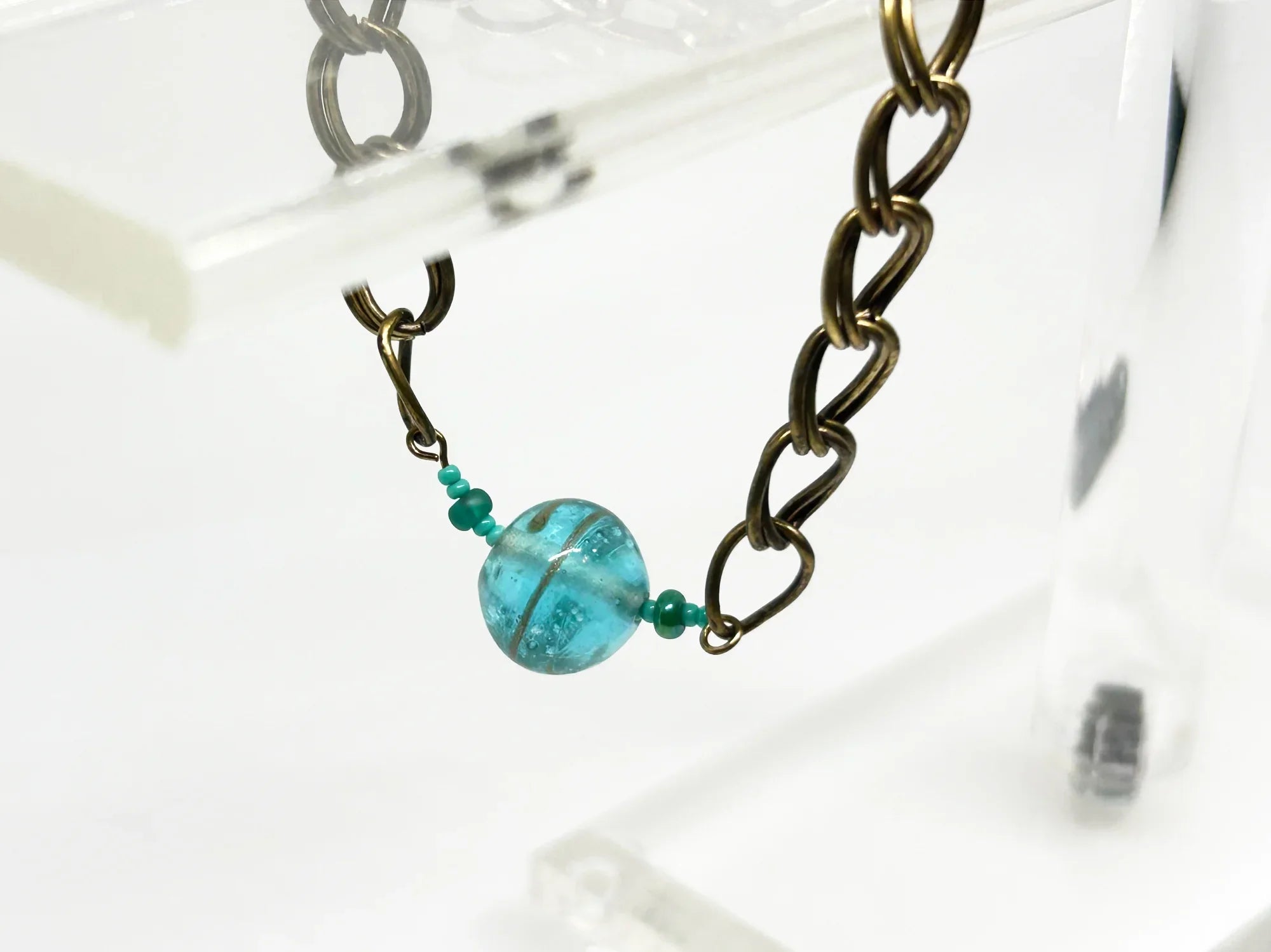 This captivating vintage bracelet boasts two rows of links on either side of a stunning blue glass marble with shimmering gold stripes. It is 7 1/2" in length and features a charming toggle clasp