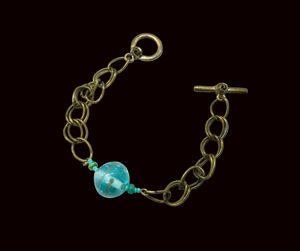 This captivating vintage bracelet boasts two rows of links on either side of a stunning blue glass marble with shimmering gold stripes. It is 7 1/2" in length and features a charming toggle clasp