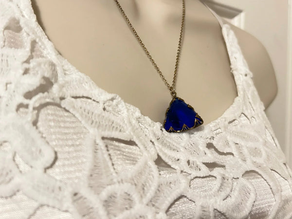 This extraordinary art deco pendant necklace is fashioned from a triangular, faceted piece of cobalt blue glass that measures 3/4" on each side. It also includes a spring clasp chain that is 18" long. The necklace is in excellent condition and has a captivating blue violet hue that is complemented by an uncommon cut