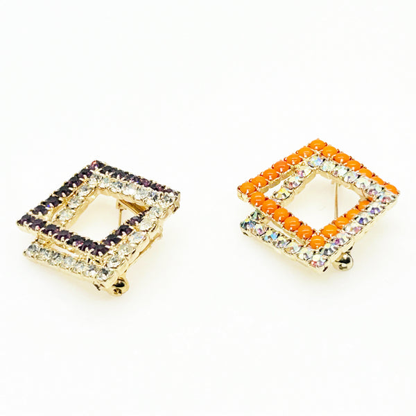 Set of two vintage 3D interlocking square brooches. One features purple and clear prong-set rhinestones on a silver-tone frame. The other features opaque orange and sparkling gold AB crystals on a gold-tone geometric frame