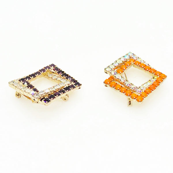 Set of two vintage 3D interlocking square brooches. One features purple and clear prong-set rhinestones on a silver-tone frame. The other features opaque orange and sparkling gold AB crystals on a gold-tone geometric frame