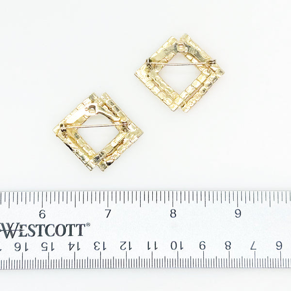 Set of two vintage 3D interlocking square brooches. One features purple and clear prong-set rhinestones on a silver-tone frame. The other features opaque orange and sparkling gold AB crystals on a gold-tone geometric frame