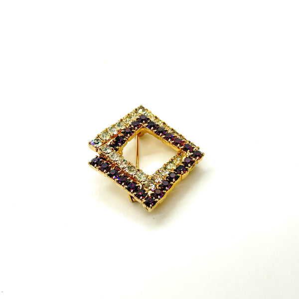 Set of two vintage 3D interlocking square brooches. One features purple and clear prong-set rhinestones on a silver-tone frame. The other features opaque orange and sparkling gold AB crystals on a gold-tone geometric frame