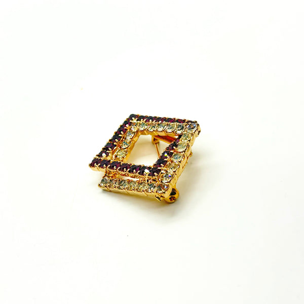 Set of two vintage 3D interlocking square brooches. One features purple and clear prong-set rhinestones on a silver-tone frame. The other features opaque orange and sparkling gold AB crystals on a gold-tone geometric frame