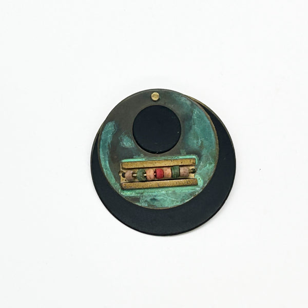 Intriguing modernist brooch with layered circular components, including a dark, possibly rubber or ebonized material, and a verdigris-patinated or painted metal plate.