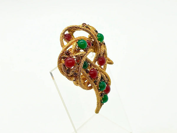 1960s vintage Capri openwork curl brooch featuring textured gold-tone metal set with green faux jade and red carnelian glass cabochons