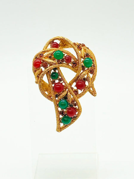 1960s vintage Capri openwork curl brooch featuring textured gold-tone metal set with green faux jade and red carnelian glass cabochons