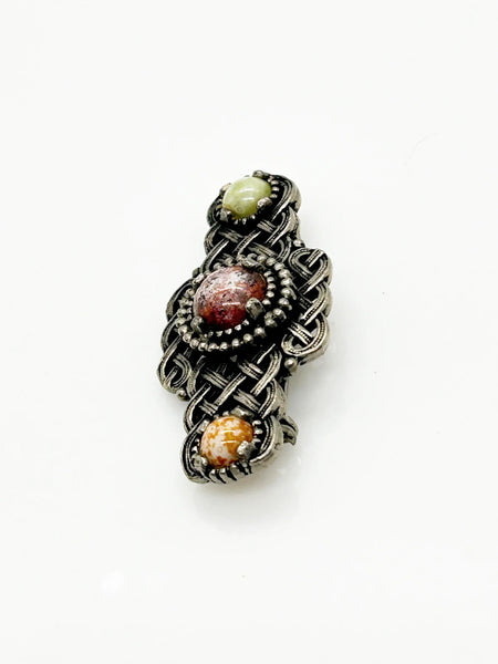 Embellish your style with the elegant and enduring Vintage Celtic Knot Style Brooch Art Glass. This beautifully crafted brooch features textured metal encasing stunning round stones in shades of pale green, red, and gold-amber. Measuring at 1.75", this accessory will add a touch of sophistication to any ensemble. Perfect for those seeking a refined and timeless addition to their collection.
