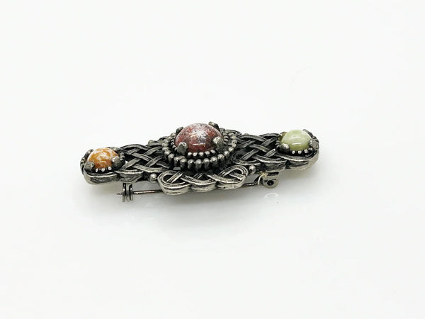 Embellish your style with the elegant and enduring Vintage Celtic Knot Style Brooch Art Glass. This beautifully crafted brooch features textured metal encasing stunning round stones in shades of pale green, red, and gold-amber. Measuring at 1.75", this accessory will add a touch of sophistication to any ensemble. Perfect for those seeking a refined and timeless addition to their collection.