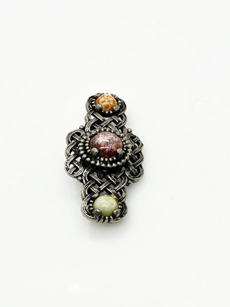 Embellish your style with the elegant and enduring Vintage Celtic Knot Style Brooch Art Glass. This beautifully crafted brooch features textured metal encasing stunning round stones in shades of pale green, red, and gold-amber. Measuring at 1.75", this accessory will add a touch of sophistication to any ensemble. Perfect for those seeking a refined and timeless addition to their collection.