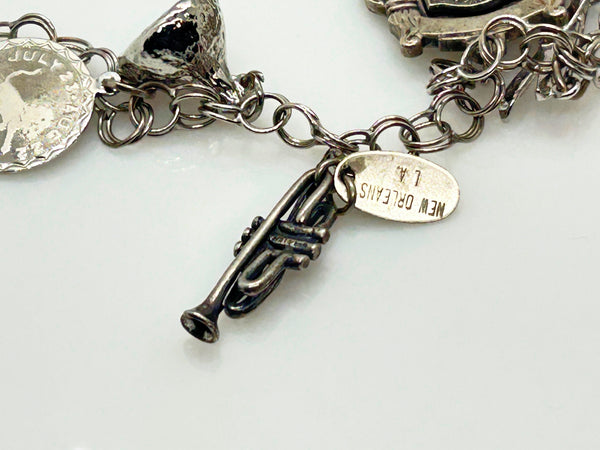 Silver charm bracelet with various charms on a white background