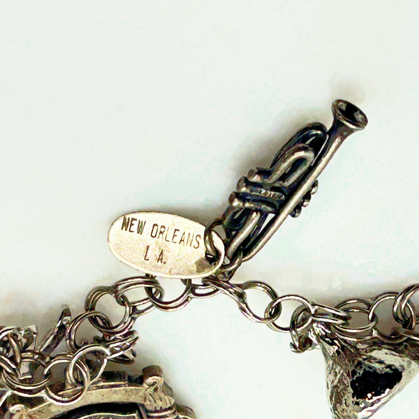Silver charm bracelet with various charms on a white background