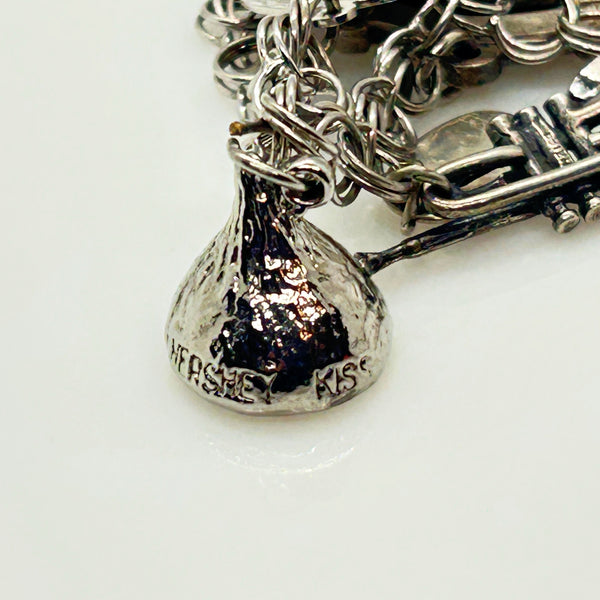 Silver charm bracelet with various charms on a white background