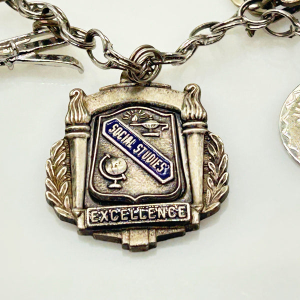 Silver charm bracelet with various charms on a white background