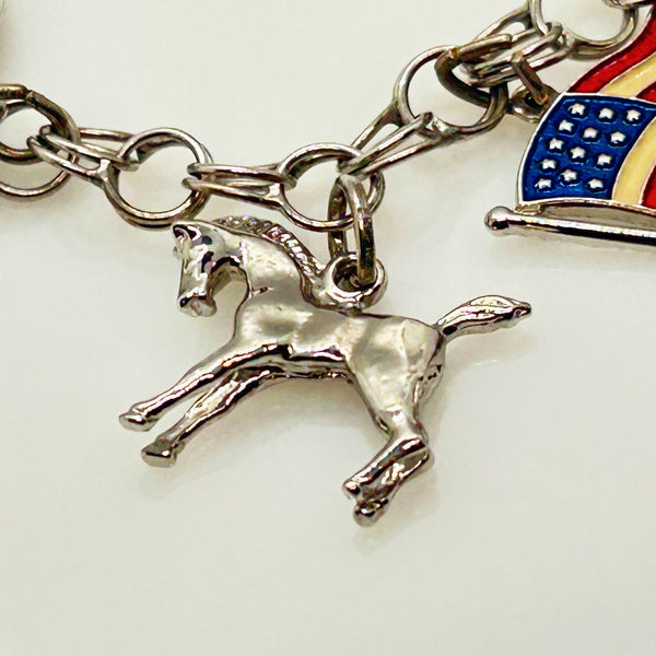 Silver charm bracelet with various charms on a white background
